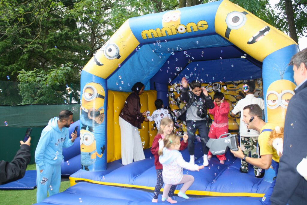 Lots of children on the bouncy castle at the family fun day with an entertainer using a bubble machine