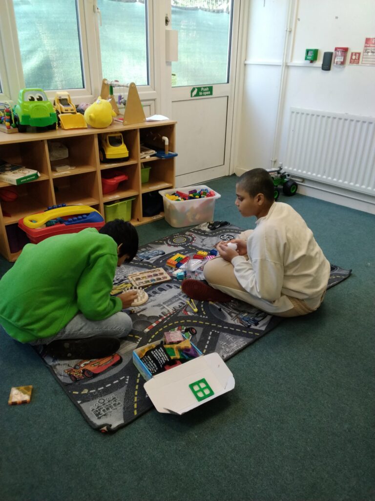 Two children sitting on the floor playing with cars and games